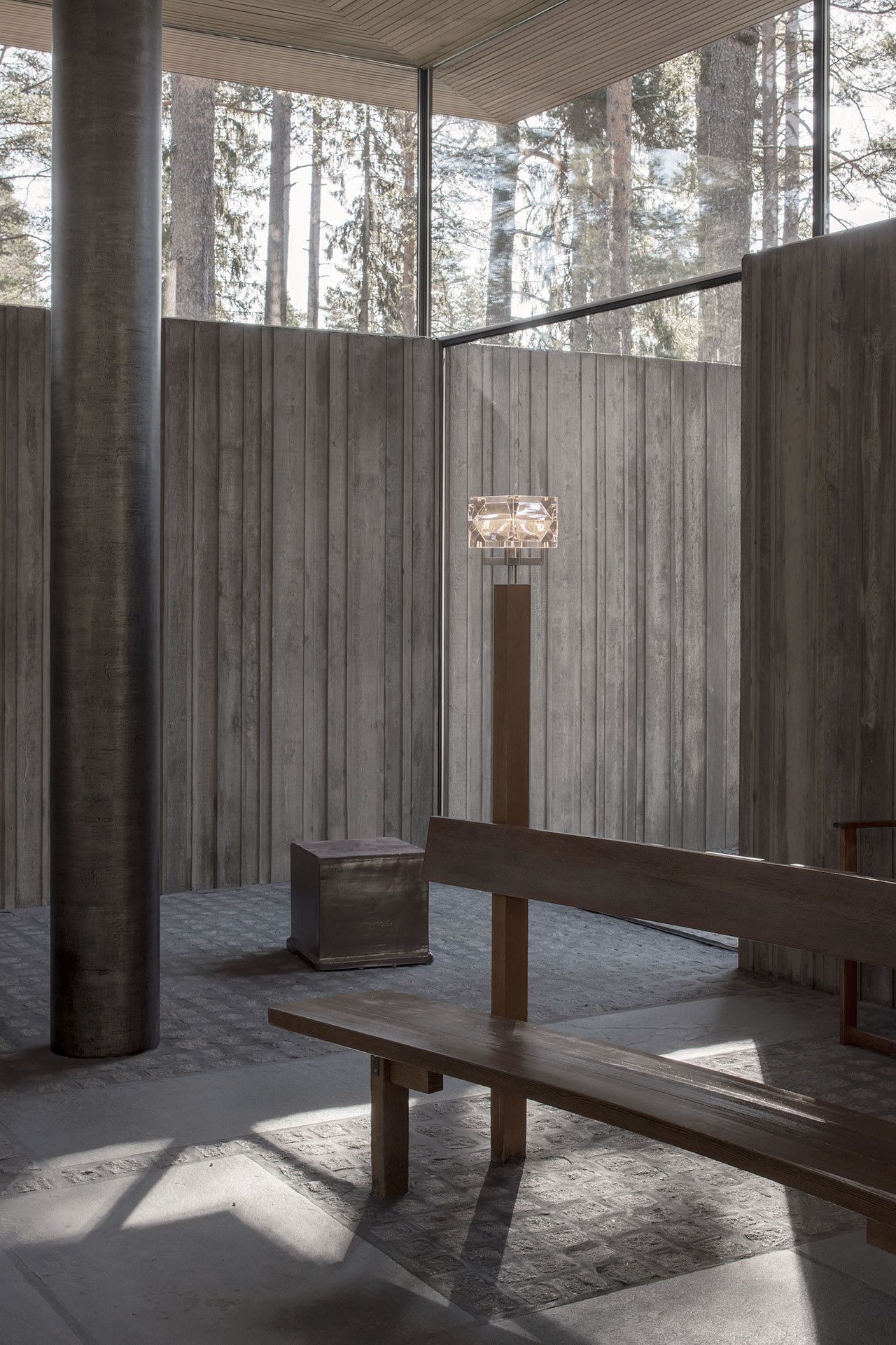Gävle Crematorium by ELLT captured by Andy Liffner — The crematorium's courtyard chapel frames a deliberate spatial sequence: weathered concrete walls with visible aging patina create a monolithic enclosure,...