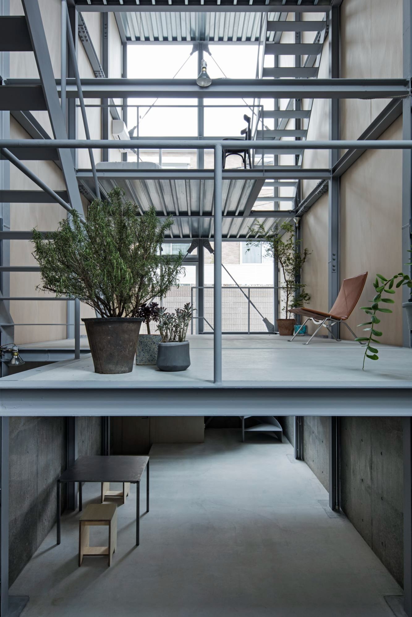 Ebisu No Ie by Tetsuo Yamaji Architects — A double-height interior showcases the modular steel framework of Ebisu No Ie, with corrugated metal ceiling panels overhead and a diagonal metal staircase...