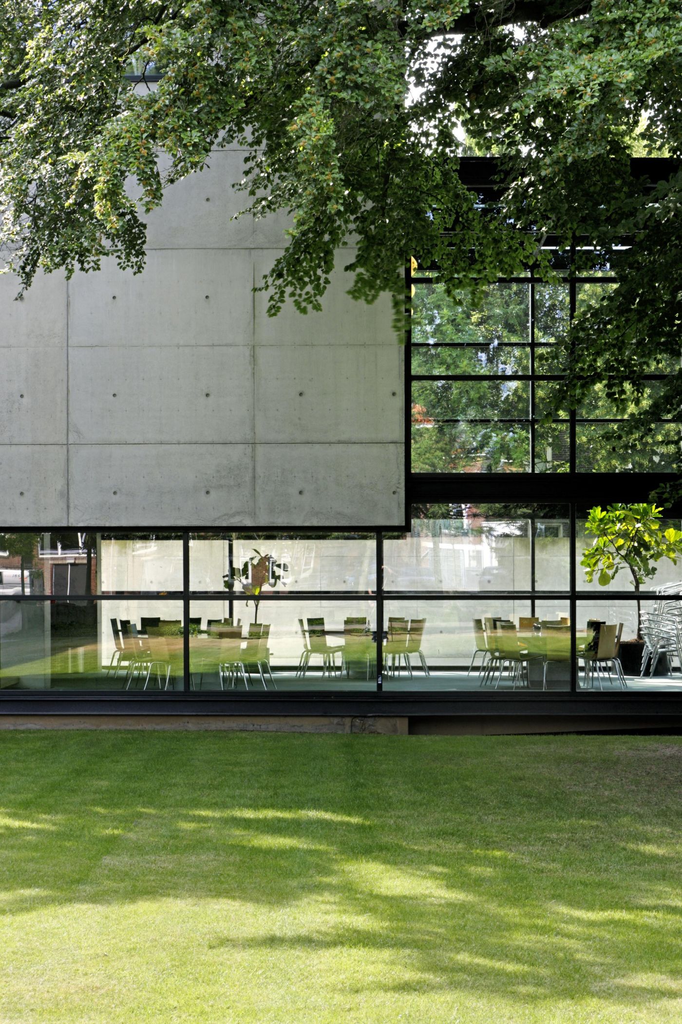 AZL Pension Fund Headquarters by Wiel Arets Architects by WAA Wiel Arets Architects — The AZL Pension Fund Headquarters presents a monolithic concrete facade with board-marked texture and horizontal joints, cantilevered over a recessed...