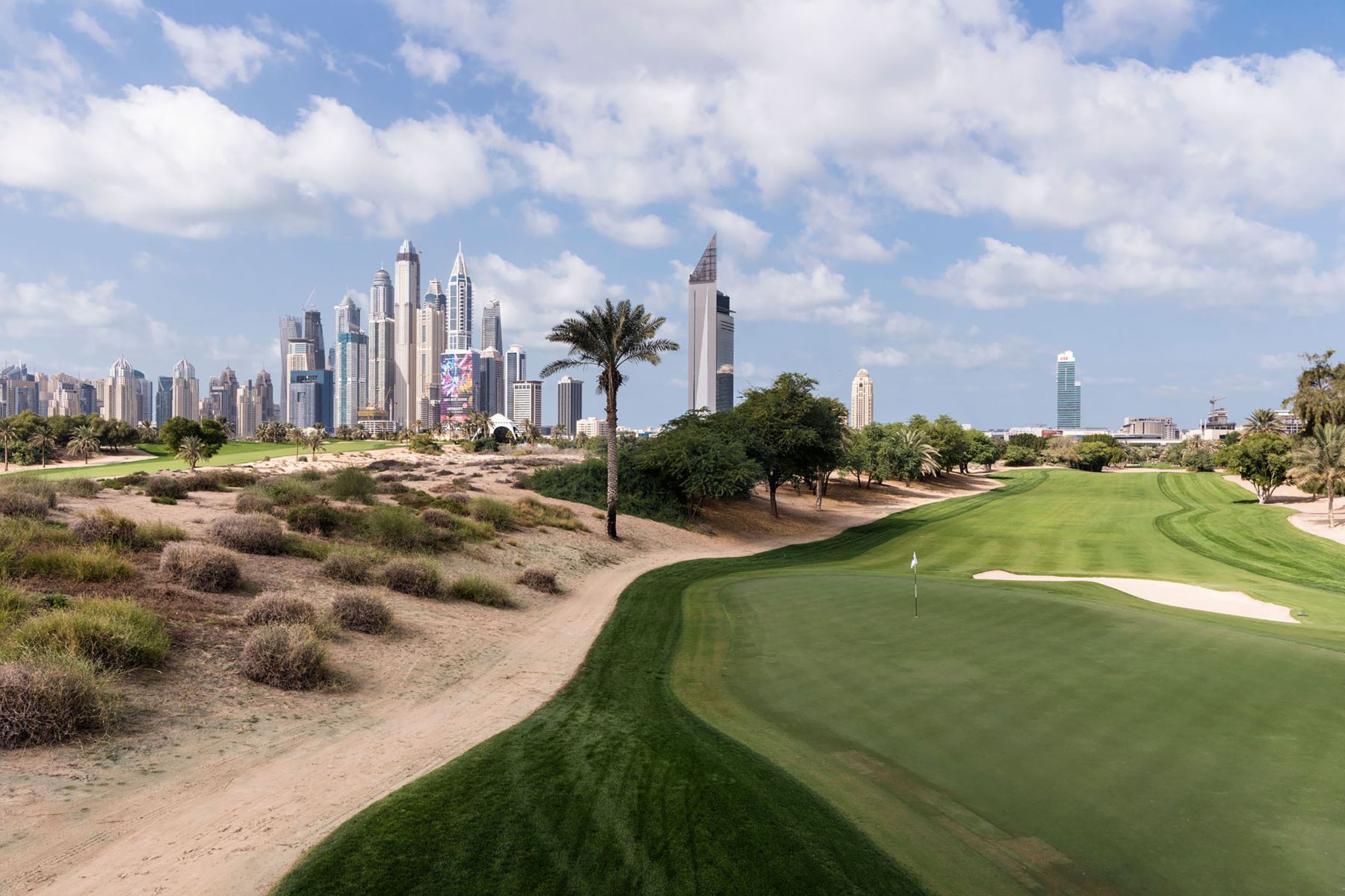 Garden of Delight by Nick Hannes — A manicured golf course in the foreground with precise geometric fairways and sand bunkers transitions sharply into desert scrubland dotted with sparse...