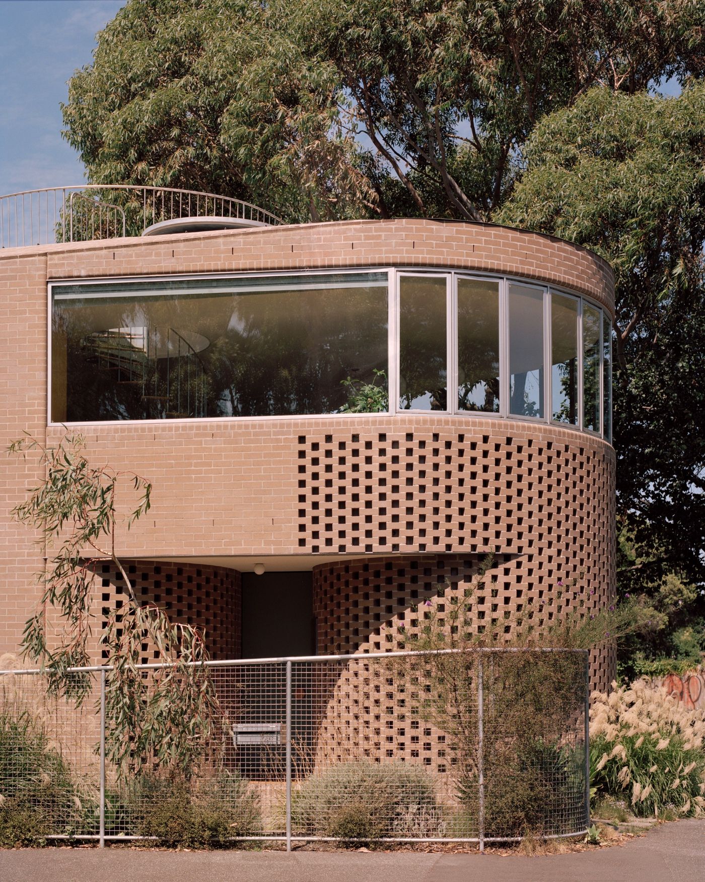 Rose House by Baracco+Wright Architects — A cylindrical brick tower dominates this composition, its terracotta masonry surface articulated by horizontal banding of perforated voids that create a...