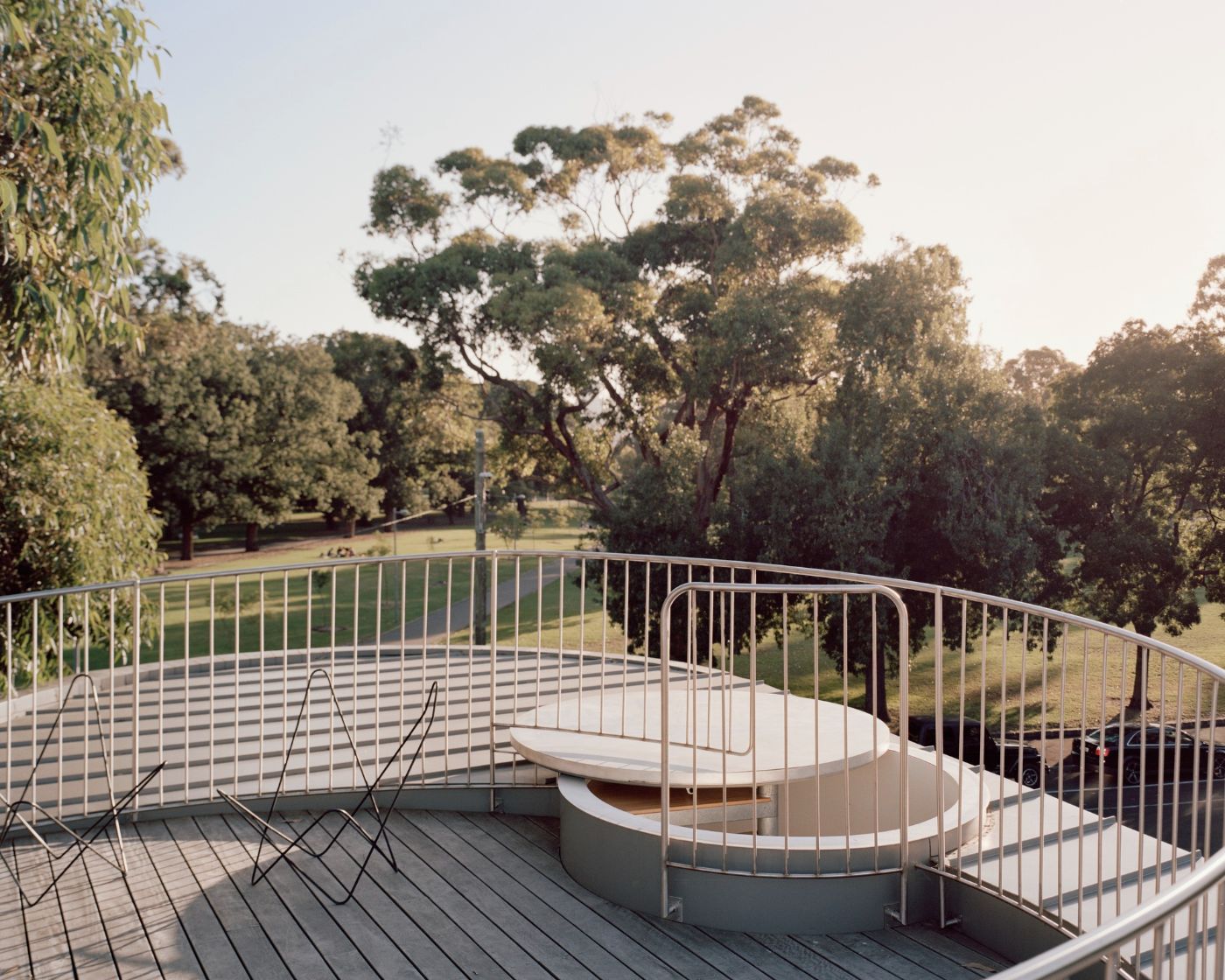 Rose House by Baracco+Wright Architects — A rooftop terrace enclosed by steel railings frames a cylindrical concrete seating element with timber detailing.