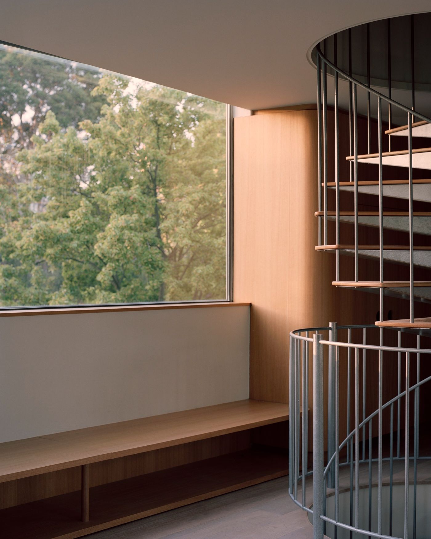 Rose House by Baracco+Wright Architects — Interior view of a spiraling staircase with timber treads and steel balustrade defining the double-height space.