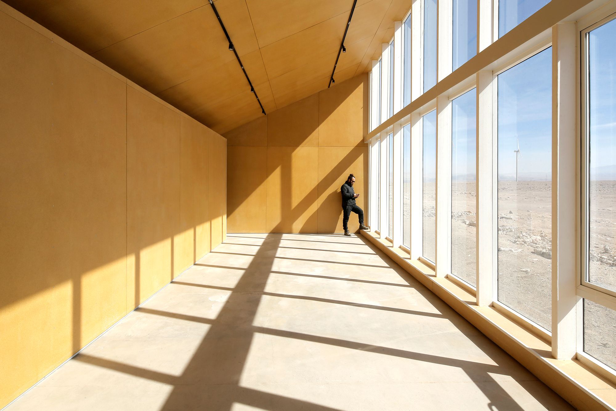 Center of Interpretation of the Desert by Emilio Marín and Juan Carlos López — A corridor flooded with golden afternoon light from floor-to-ceiling glazing reveals the desert research center's commitment to transparency and...