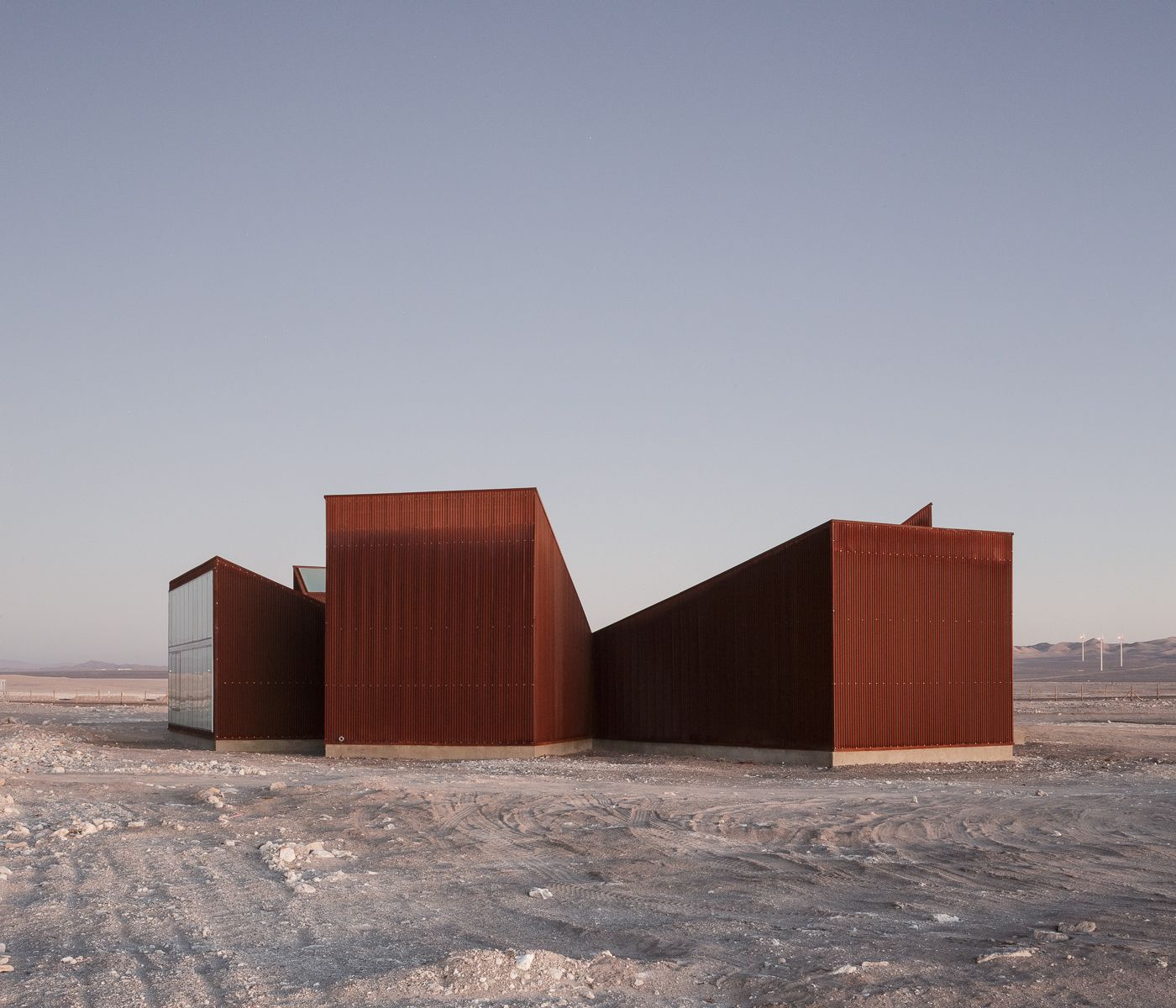 Center of Interpretation of the Desert by Emilio Marín and Juan Carlos López — Three trapezoidal volumes clad in corrugated corten steel occupy a barren desert plateau in Chile's Atacama region.