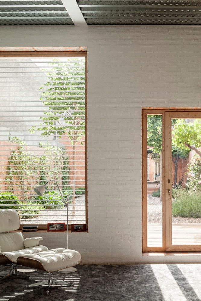 House 1014 by H Arquitectes — Interior threshold framed by timber-clad sliding doors in warm honey tone, revealing a recessed courtyard beyond.