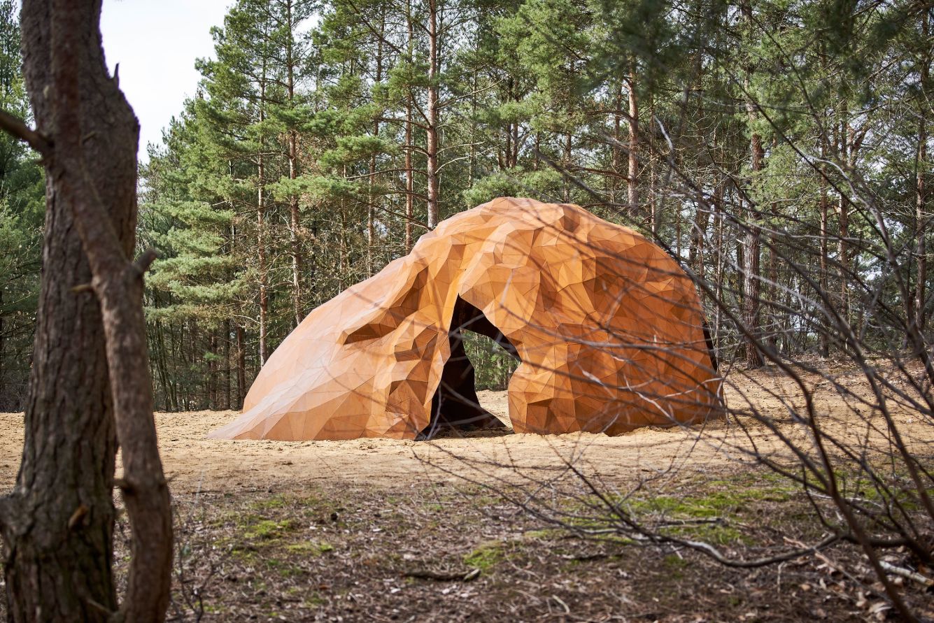 A Giant Sculpture by Gijs Van Vaerenbergh — A monumental welded-steel sculpture dominates a sunken sandy clearing in a coniferous forest.