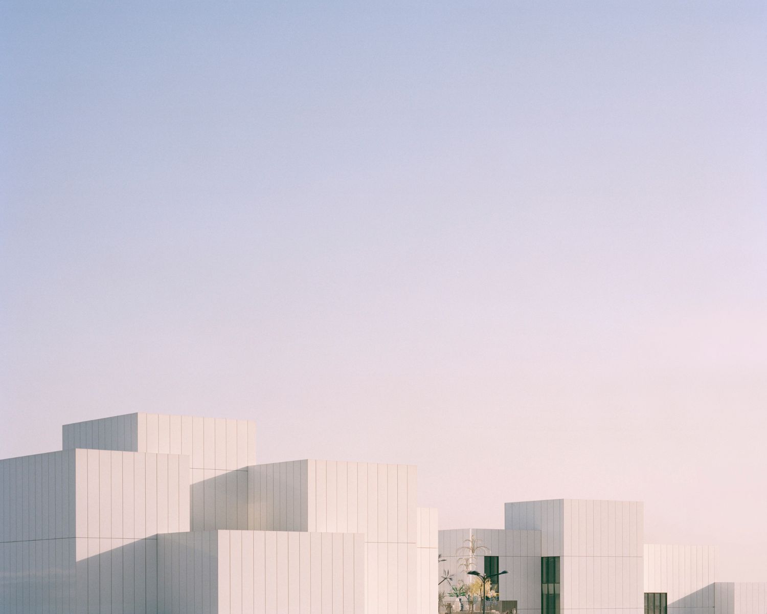 Jameel Arts Centre Dubai by Serie Architects — Evening light catches the Jameel Arts Centre's staggered facade, illuminating the corrugated aluminum cladding with vertical ribbing in cream tones.