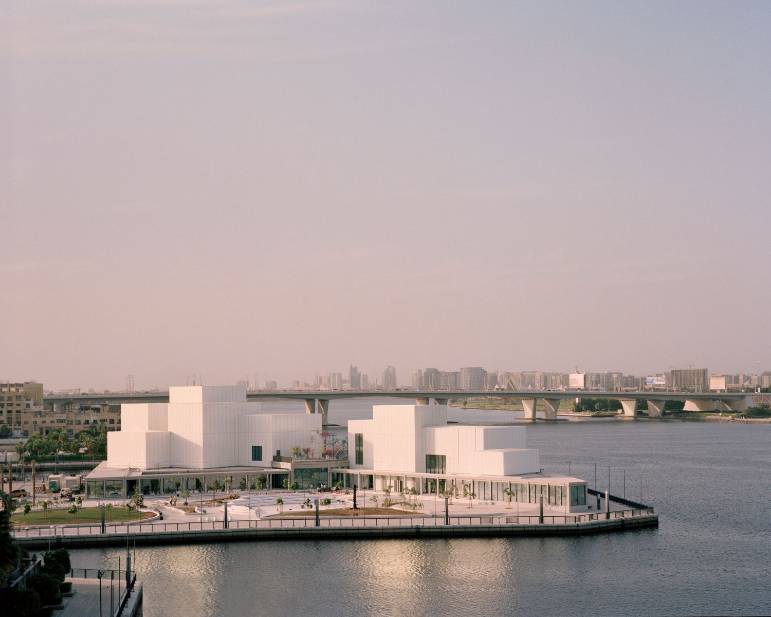 Jameel Arts Centre Dubai by Serie Architects — The Jameel Arts Centre's waterfront facade dominates this view, its corrugated aluminum cladding with vertical ribbing rendered in white.