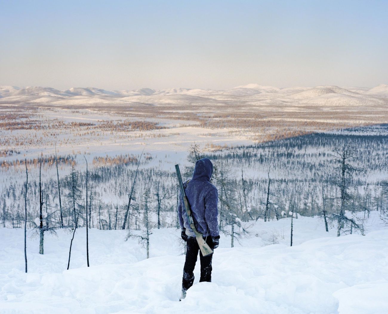 Sacha by Alexis Pazoumian — A figure stands on snow-covered ground overlooking vast tundra landscape in Yakutia, eastern Siberia.