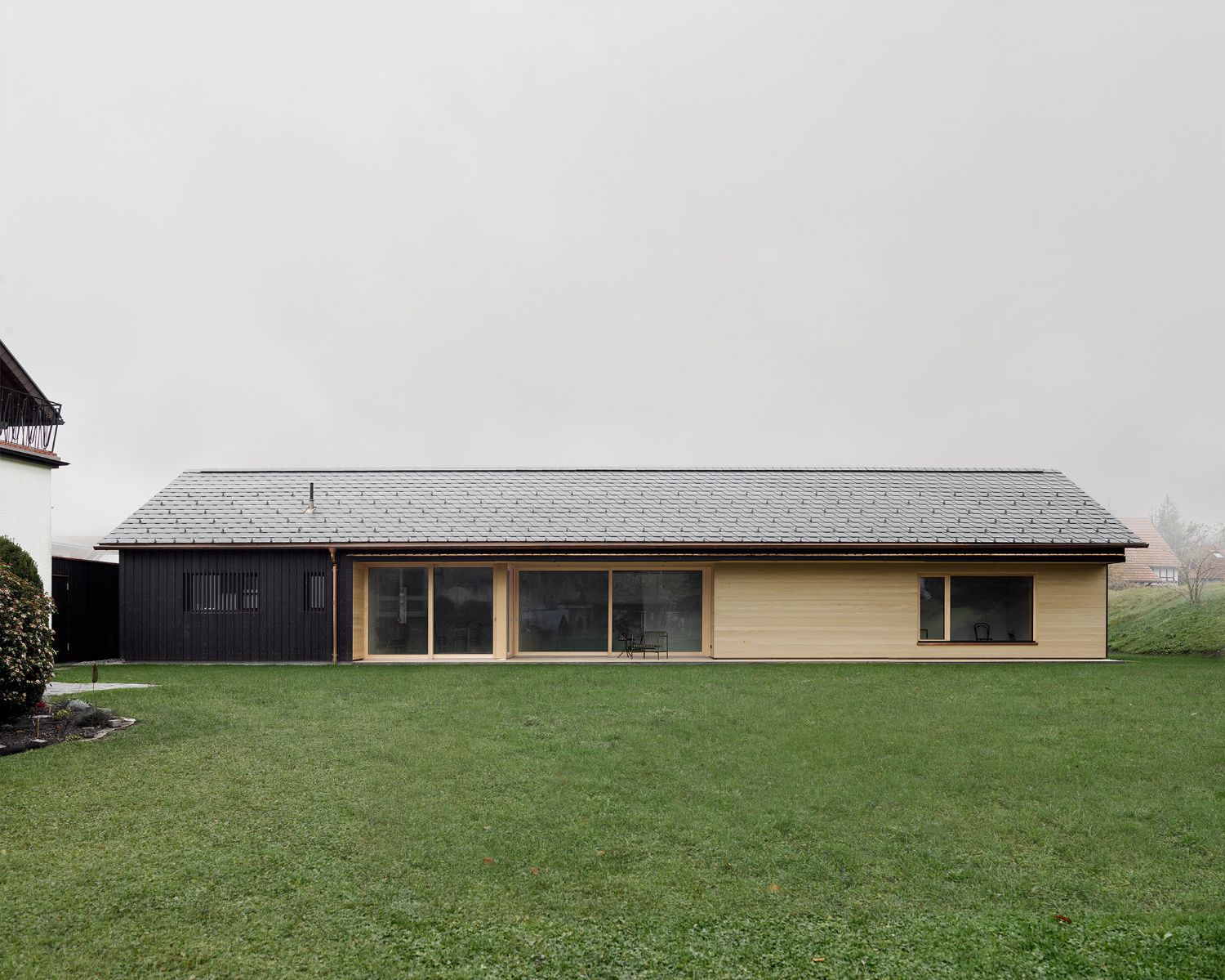 House ZF by Bernd Riegger — The elongated single-storey residence presents a restrained facade combining materiality and transparency.
