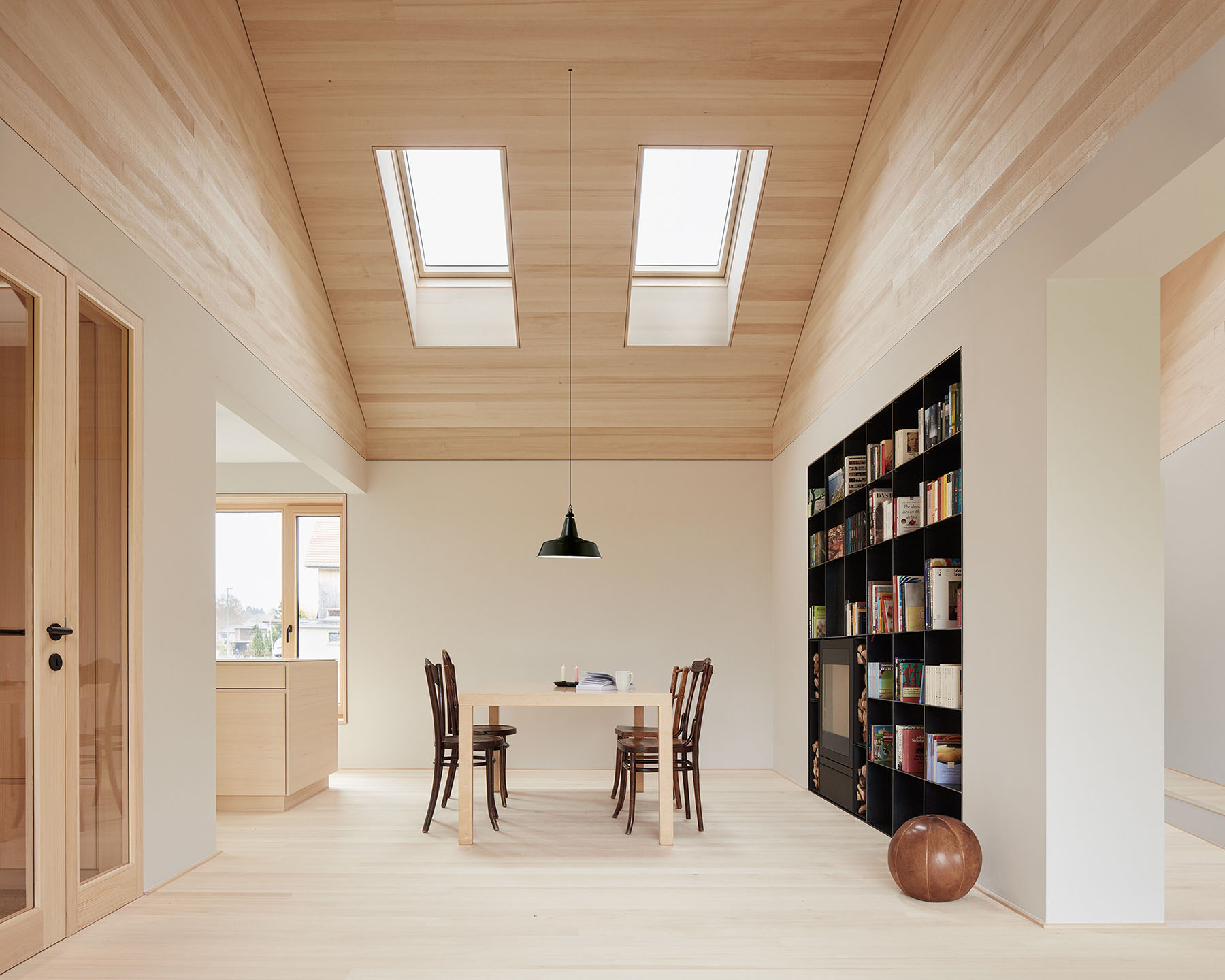 House ZF by Bernd Riegger — A single-storey interior living space featuring two rectangular skylights inset into a warm timber ceiling with visible structural framing, flooding the...