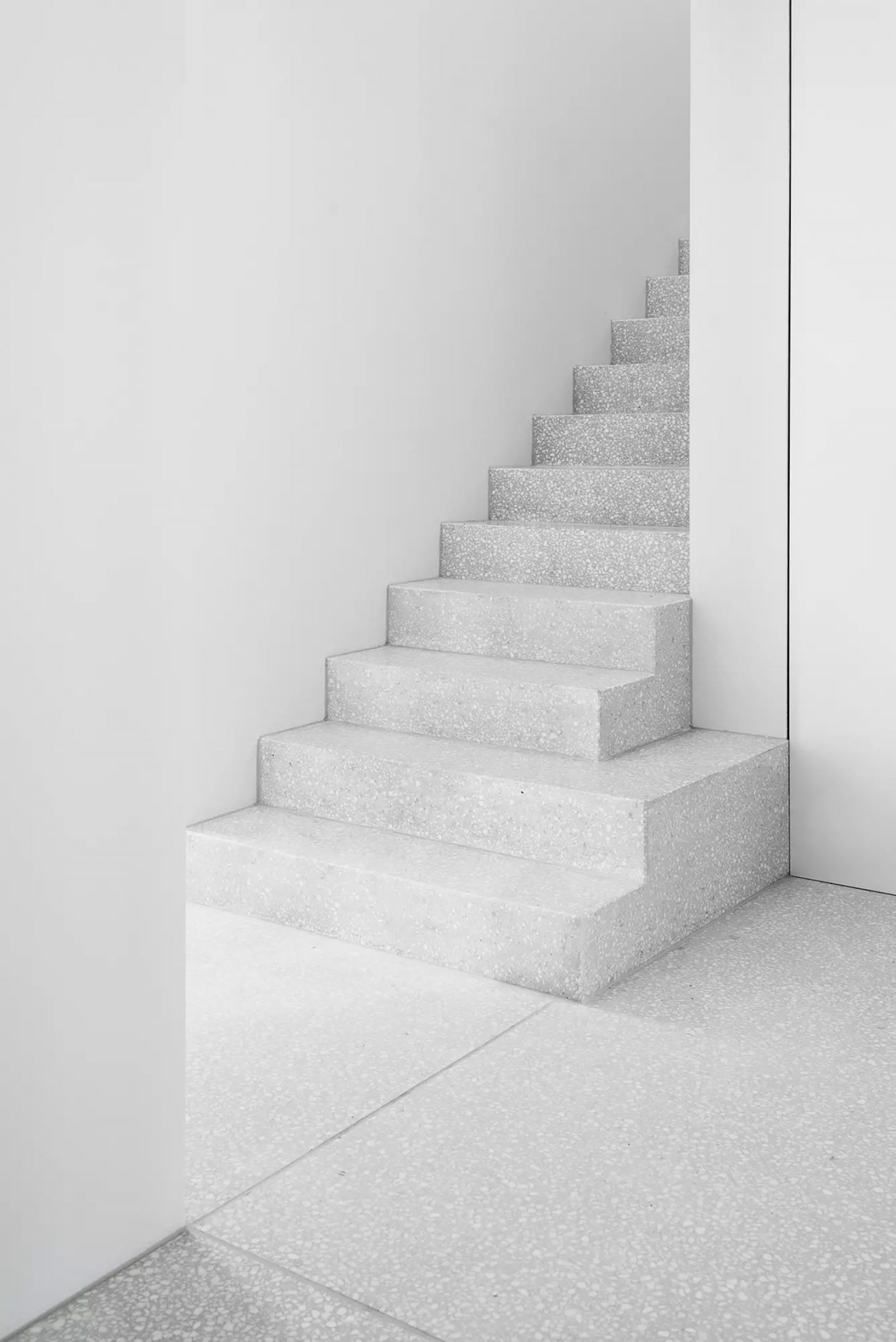 House for an Art Collector by Think Architecture — A cantilevered concrete staircase ascends through a minimal white-walled interior, demonstrating a deliberate material hierarchy.