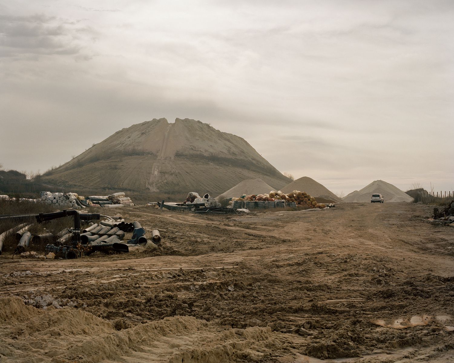 Along the Swift Current of Time by Teodora Georgieva — Industrial extraction site in Devnya, Bulgaria, dominated by three conical tailings mounds composed of mineral deposits.