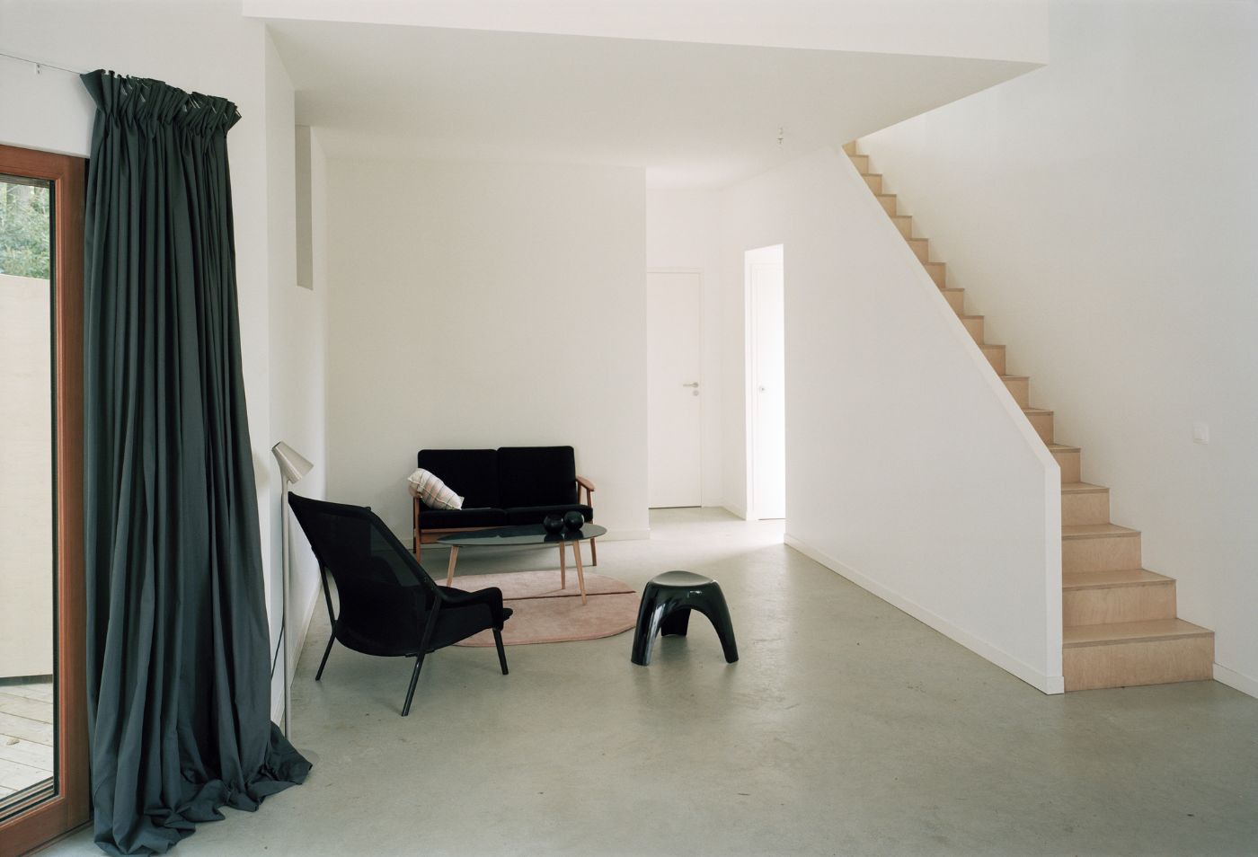 Holiday House in Sarzeau by RAUM — A double-height interior volume with polished concrete flooring and white-painted walls.