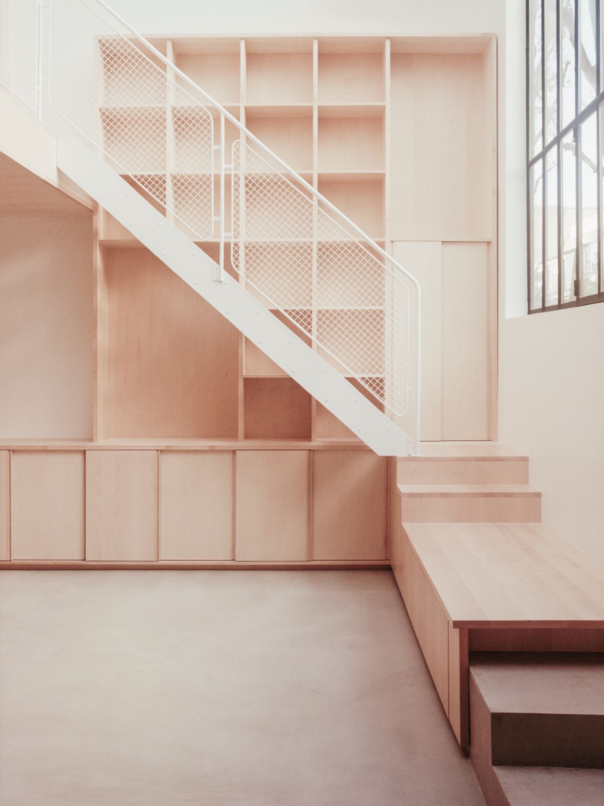 Jean Moulin Atelier – House by Atelier NEA — A double-height interior space dominated by a white-painted steel staircase with mesh safety paneling, ascending diagonally across the composition.