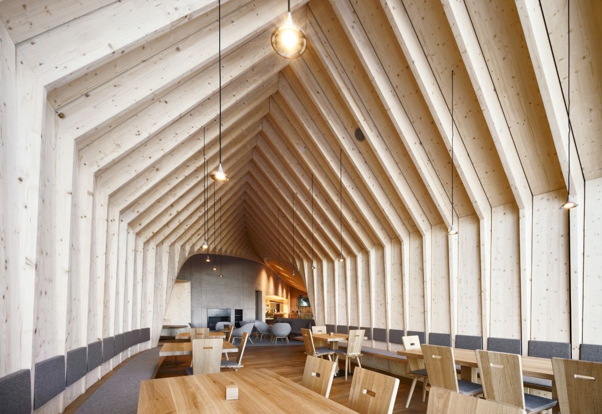 Oberholz Mountain Hut by Peter Pichler & Pavol Mikolajcak by Peter Pichler Architecture — Interior view down the length of the Oberholz Mountain Hut's dining pavilion, revealing the distinctive post-and-beam timber structure supporting white...