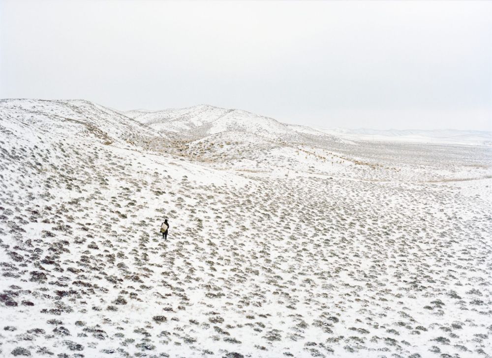Watering My Horse by Xiaoxiao Xu — A solitary figure traverses a snow-dusted slope of the Ming dynasty wall section, their dark silhouette emphasizing the vast expanse of the fortification's...