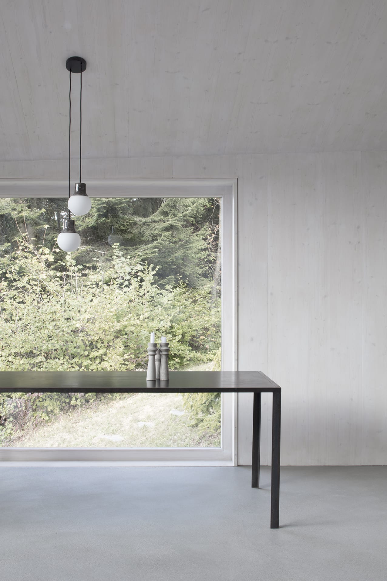 En Chalméry House by Christian Dupraz Architects — A minimalist interior threshold frames the Alpine landscape through floor-to-ceiling glazed doors with dark steel mullions.