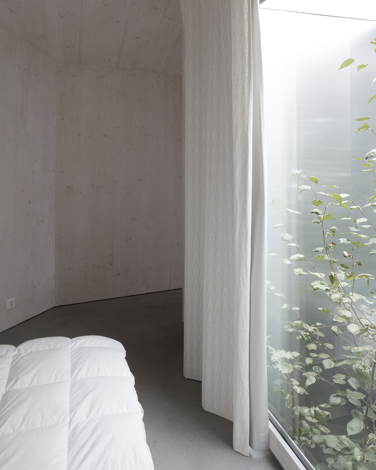 En Chalméry House by Christian Dupraz Architects — A cantilevered bed alcove with floor-to-ceiling linen curtains frames a view of the Alpine landscape beyond.