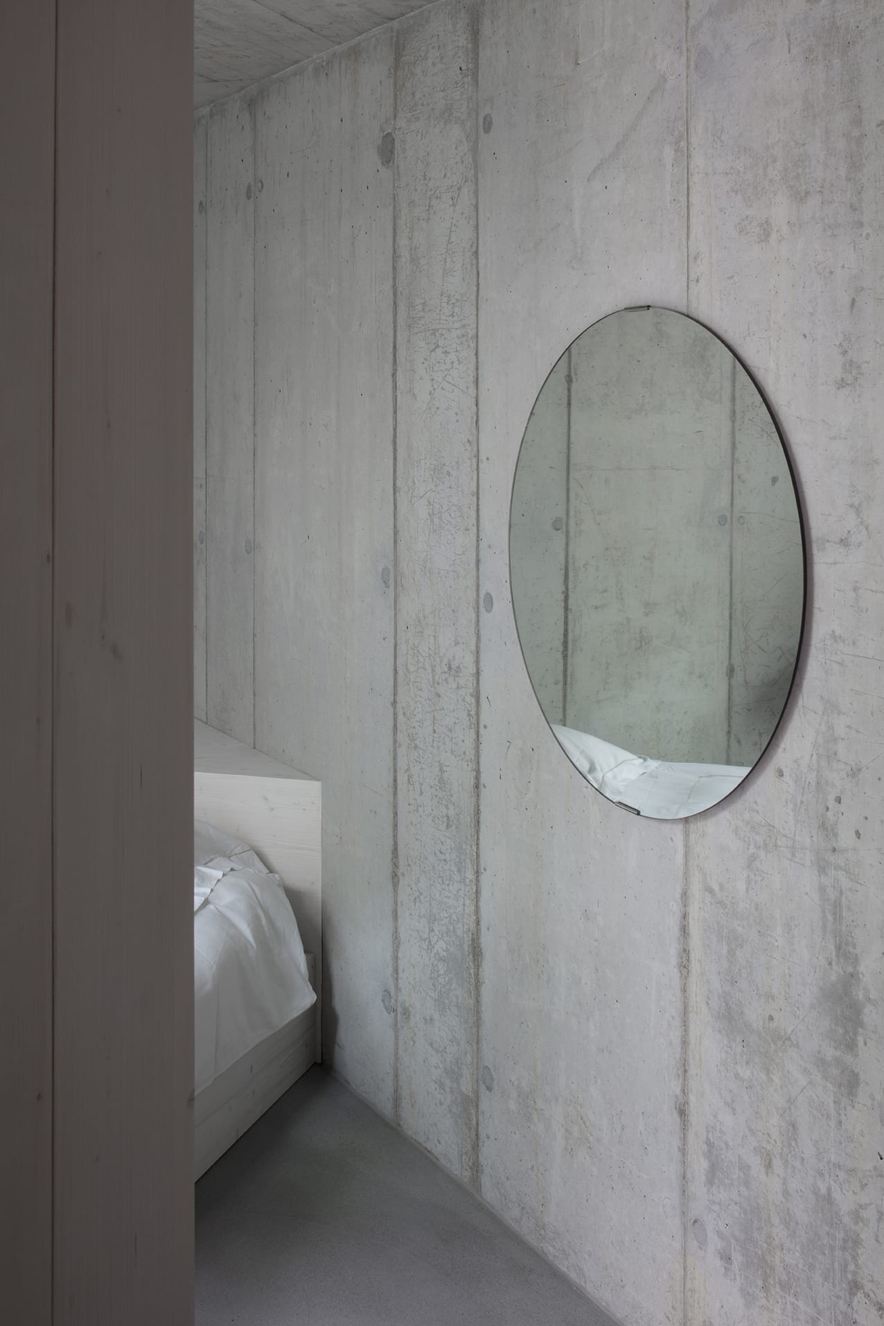 En Chalméry House by Christian Dupraz Architects — A concrete corridor interior captured in close-up, showcasing the material's monolithic board-formed surface with visible aggregate and formwork seams.