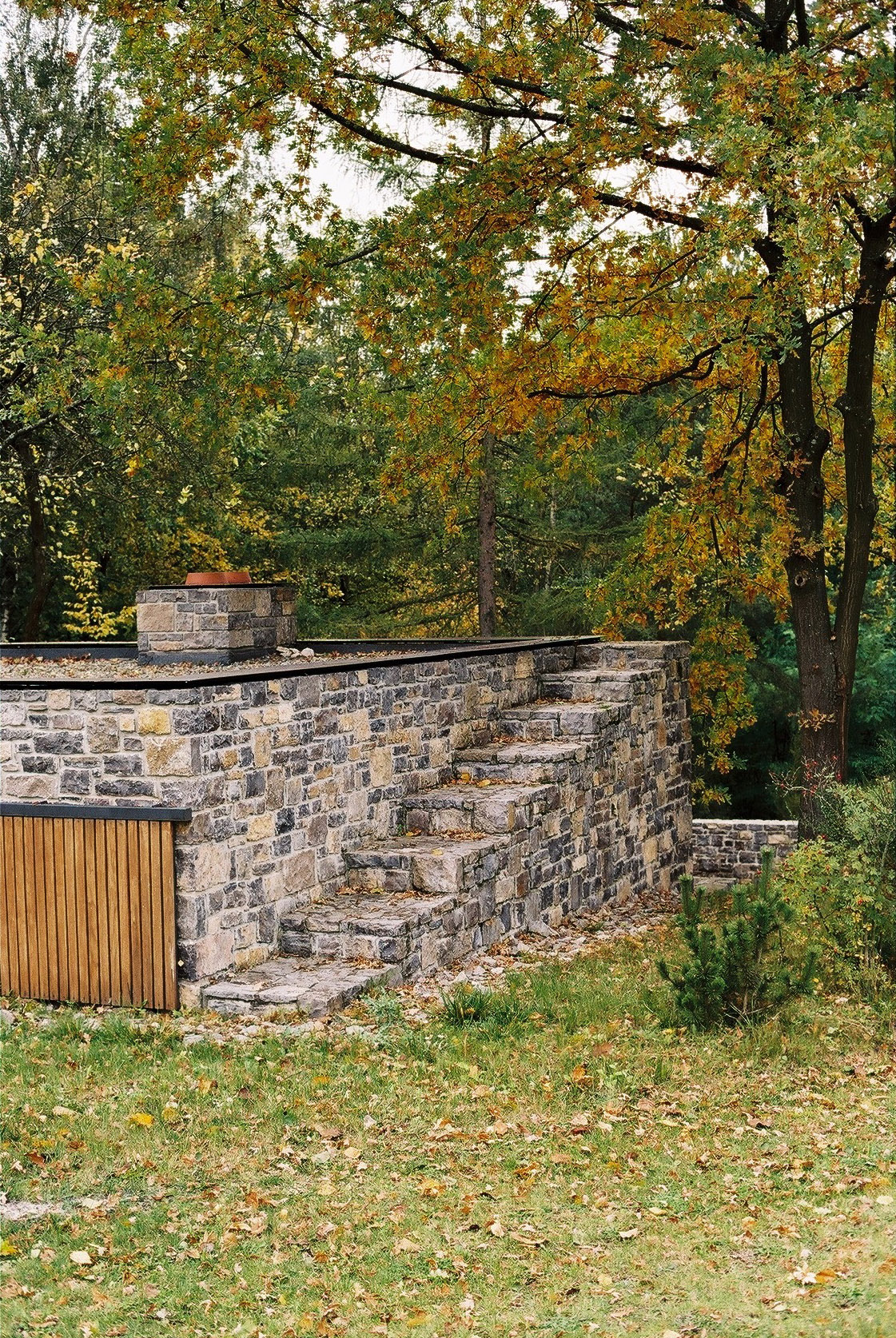 Wygnanowice House Over Crystal Clear Springs captured by Thisispaper Studio — A coursed dolomite stone staircase descends into landscape at Wygnanowice House, its warm ochre and grey tones weathered by seasonal exposure.