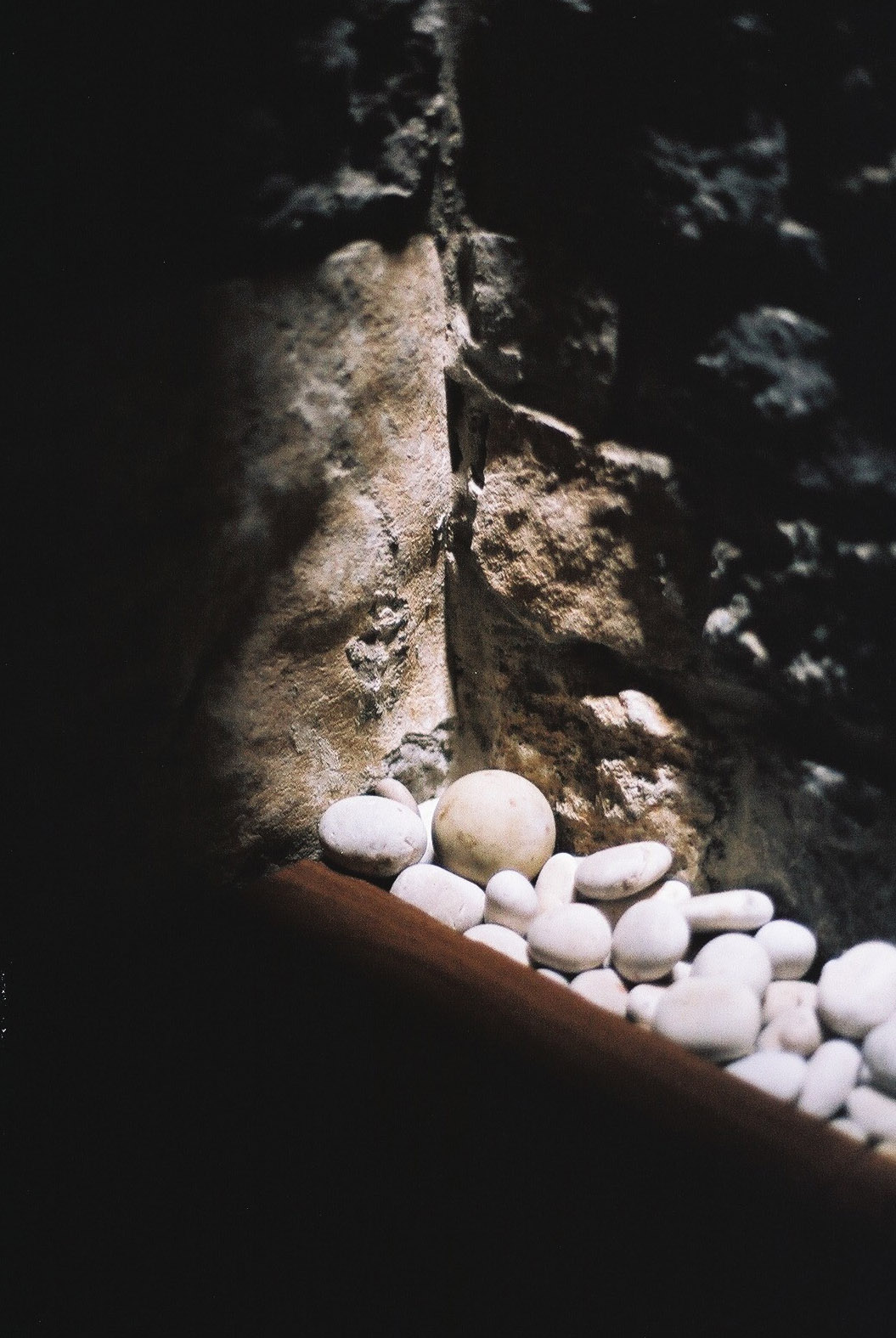 Wygnanowice House Over Crystal Clear Springs captured by Thisispaper Studio — A close-up detail of the house's foundation reveals white and cream-toned river stones accumulated against coursed dolomite masonry.