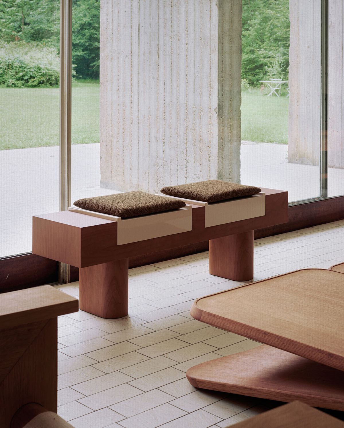 Furniture Collection by HAOS — A bench from HAOS's furniture collection demonstrates exposed timber joinery at the frame corners, with cylindrical wooden legs supporting a horizontal...