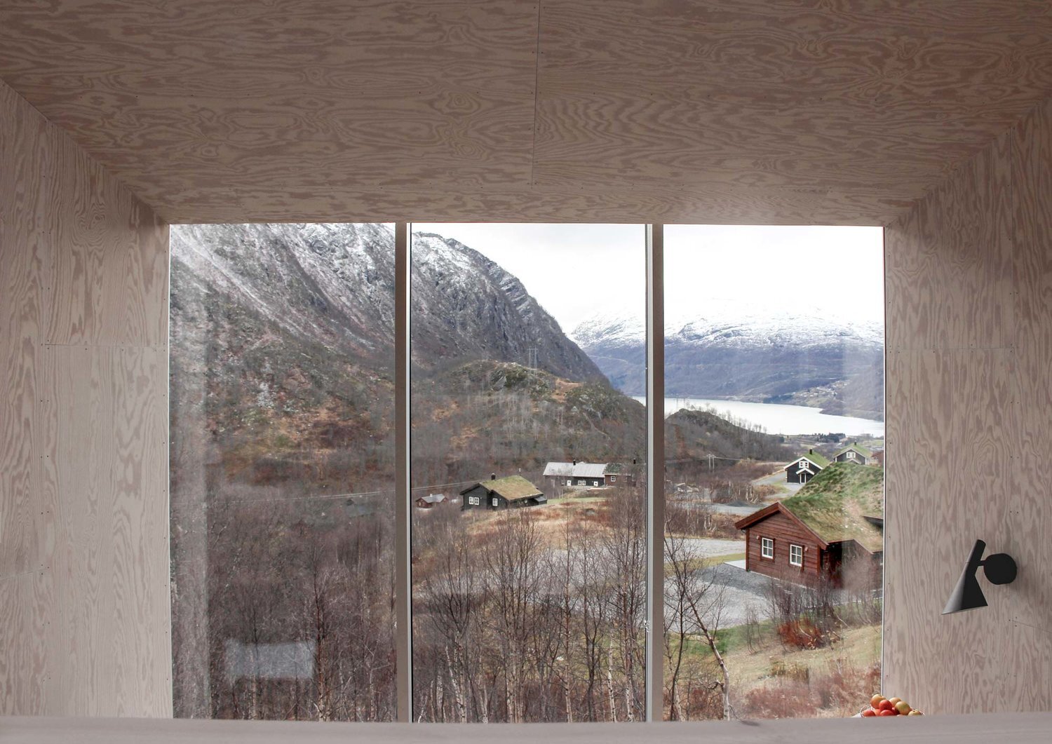 Røldal Cabin by Reiulf Ramstad Arkitekter — View from within the upper glazed volume revealing the cabin's strategic positioning within the Røldal valley landscape.