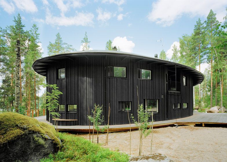 Villa Musu by Sanaksenaho Architects — Villa Musu presents as a curved, single-story pavilion wrapped in black-painted timber cladding of varying widths and thicknesses.