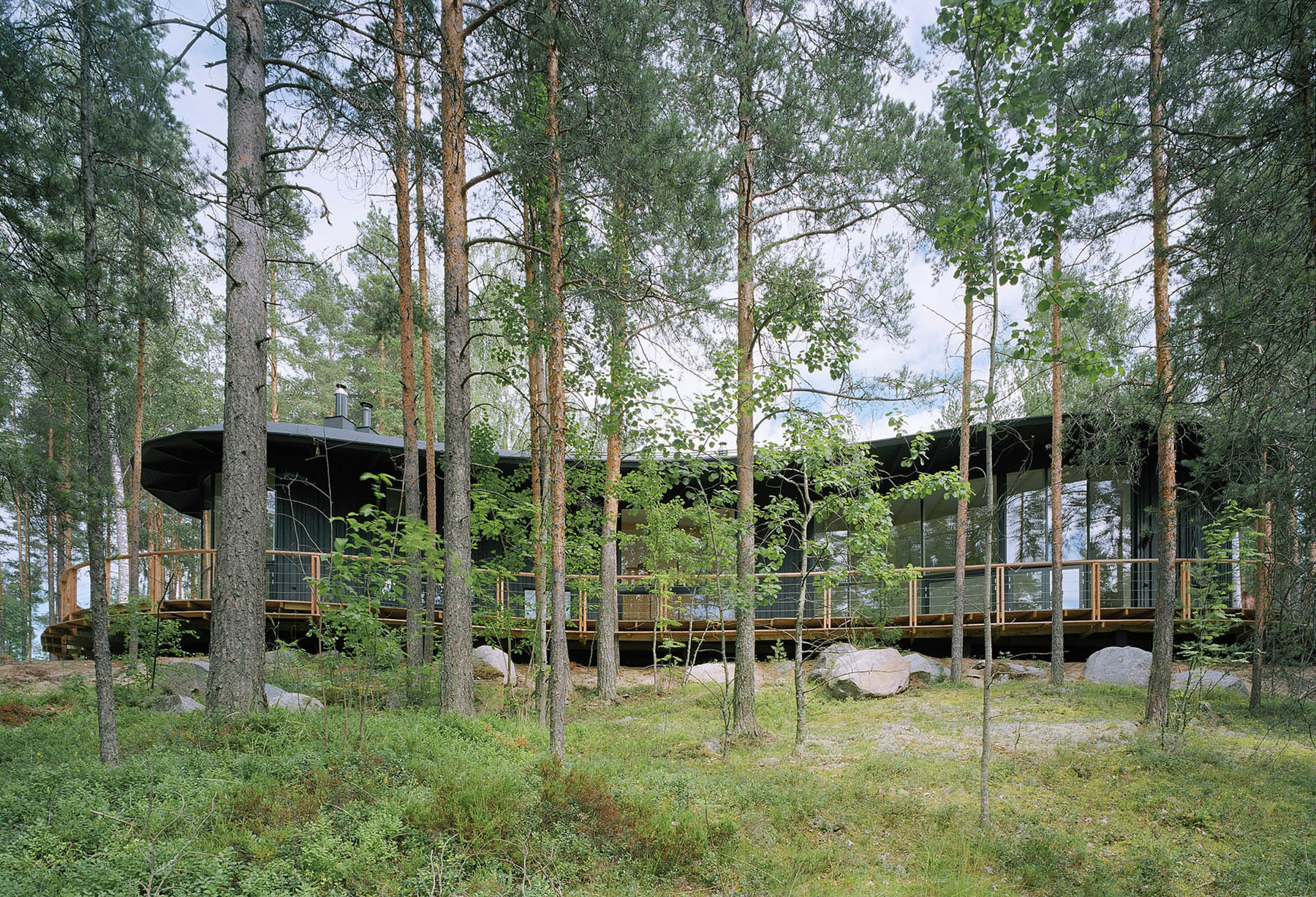 Villa Musu by Sanaksenaho Architects — Villa Musu emerges from a pine forest, its black-painted timber facade fragmented across multiple structural bays.