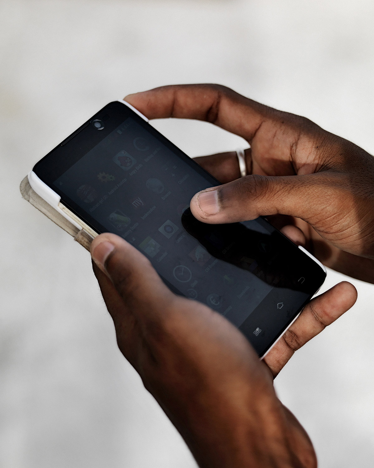 LIKE by Ryan Debolski — A close-up photograph of a hand holding a smartphone with a dark screen displaying application icons.