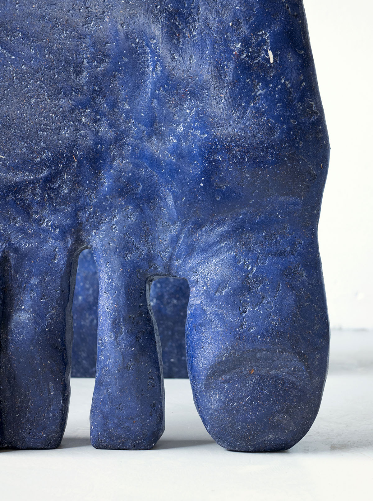 Roommates by Barbora Žilinskaite — Close-up detail of a hand-sculpted composite form revealing the junction between a tapered columnar leg and the organic torso above.