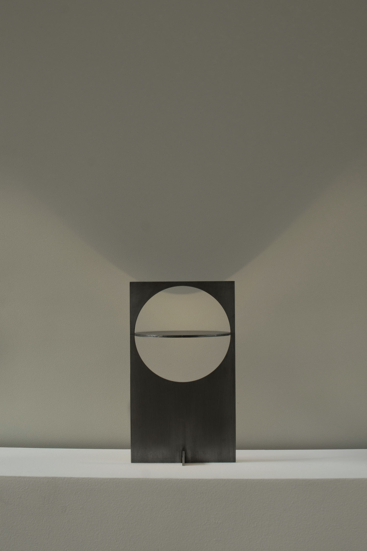 OBJ-01 by Manu Bañó — OBJ-01 presents a laser-cut steel lighting fixture mounted vertically within a dark rectangular panel frame.