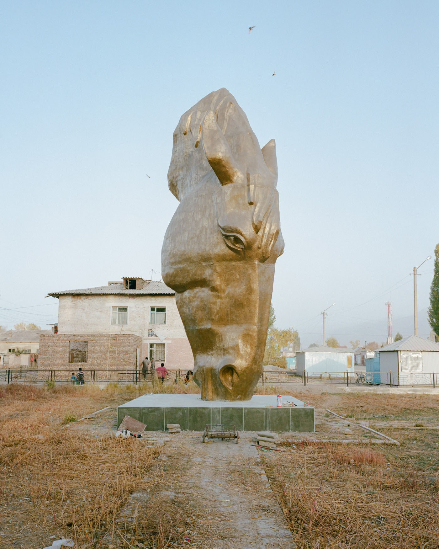 Horsehead Nebula by Matthieu Litt — A monolithic stone head sculpture dominates the arid landscape of Faristan, tilted upward with an open mouth cavity carved through the material.