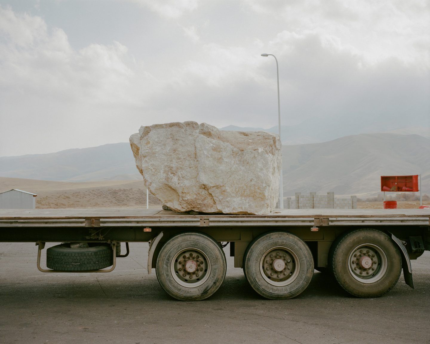 Horsehead Nebula by Matthieu Litt — A massive limestone block, weathered to cream and ochre tones, sits secured on the flatbed of a commercial truck.