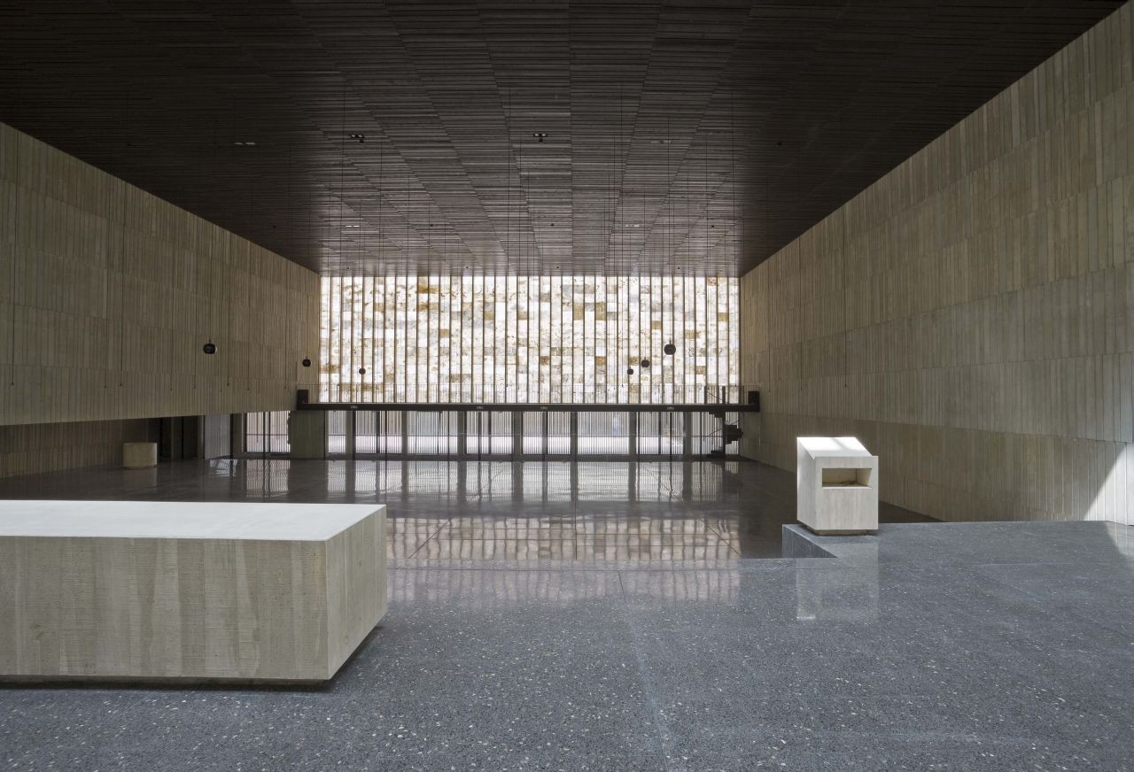 San Jorge Church by Tabuenca & Leache — The interior volume of San Jorge Church presents a rectilinear space defined by continuous vertical timber slat cladding on opposing sidewalls in cream and...