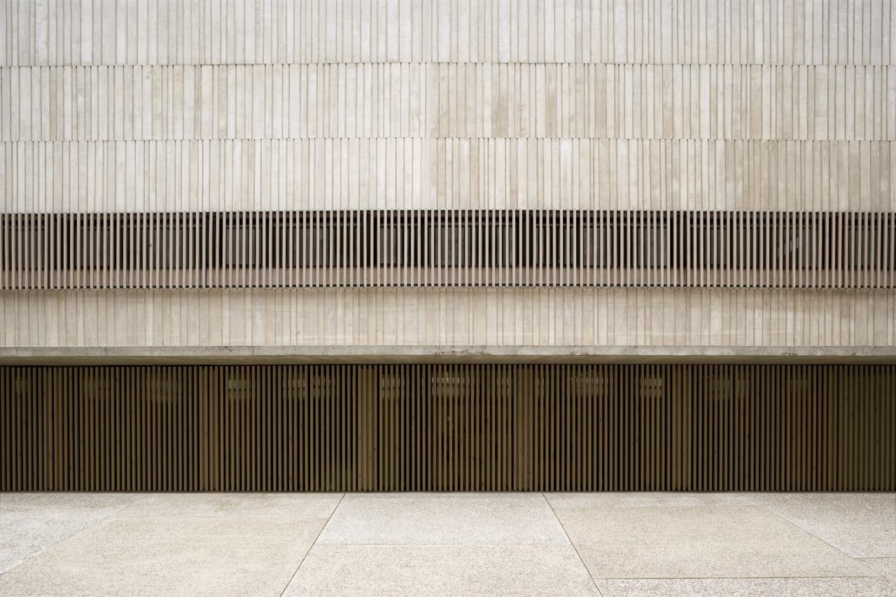 San Jorge Church by Tabuenca & Leache — The façade presents a stratified composition of horizontal timber slat screening in cream and charcoal tones.