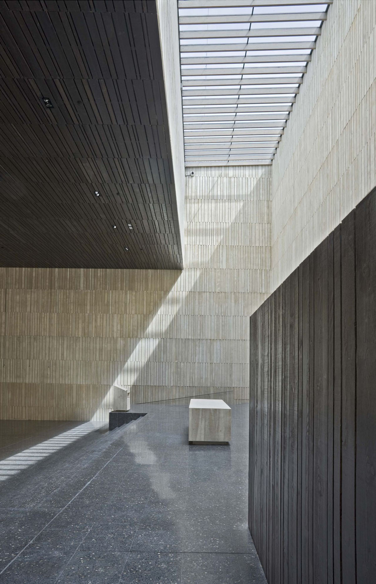 San Jorge Church by Tabuenca & Leache — A courtyard interior photographed from a covered colonnade, revealing the architectural relationship between the church's timber-clad walls and the...