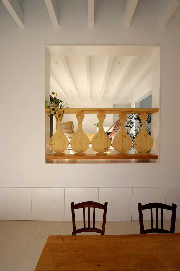 Jordi and África's House by TEd’A arquitectes — A cantilever interior opening frames a collection of wooden decorative objects against a bright upper level.