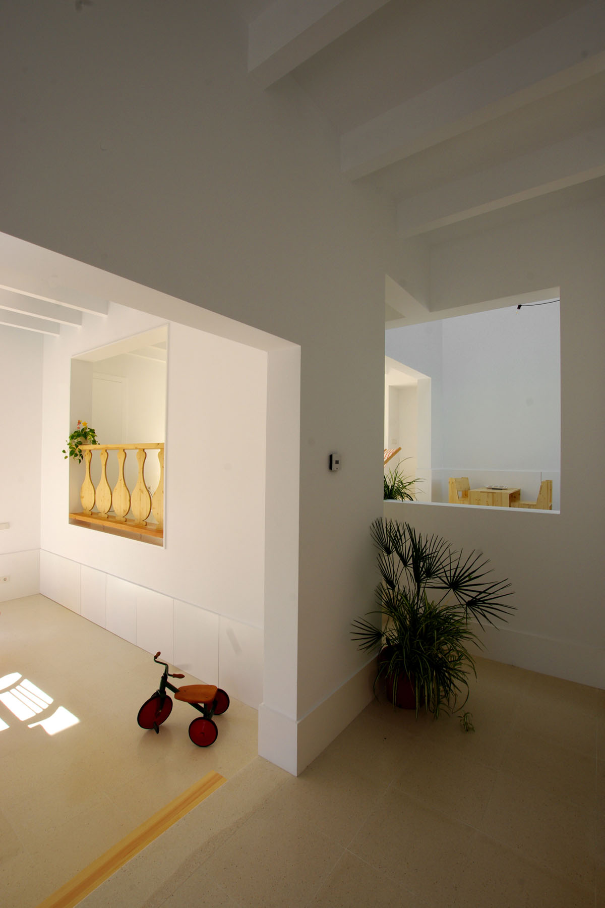 Jordi and África's House by TEd’A arquitectes — Interior passage framed by white-rendered partition walls with recessed rectangular openings.