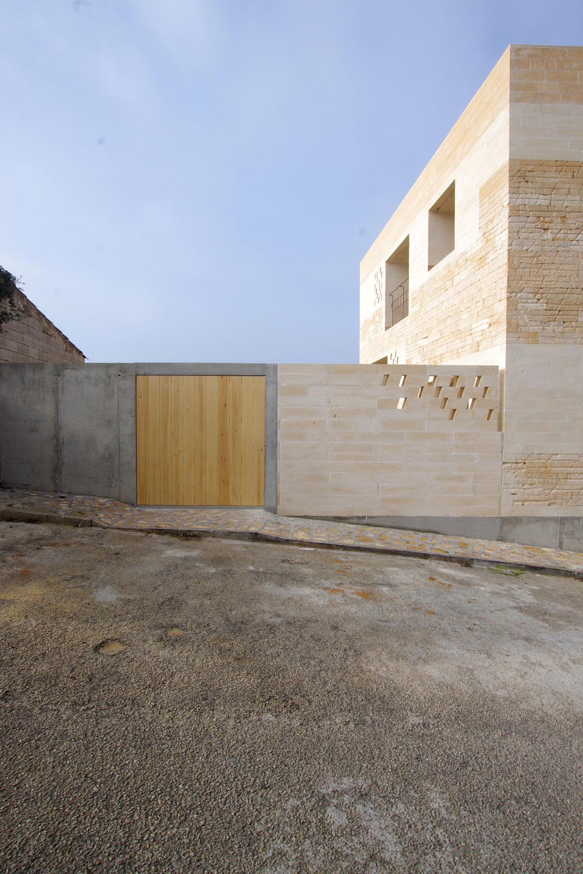 Jordi and África's House by TEd’A arquitectes — The entrance courtyard of Jordi and África's House presents a layered composition of material contrasts.