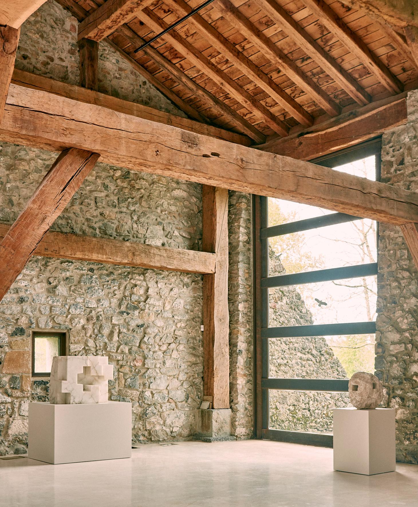 Eduardo Chillida Leku Museum — A timber-framed interior within stone walls displays sculptural works on white cubic pedestals.