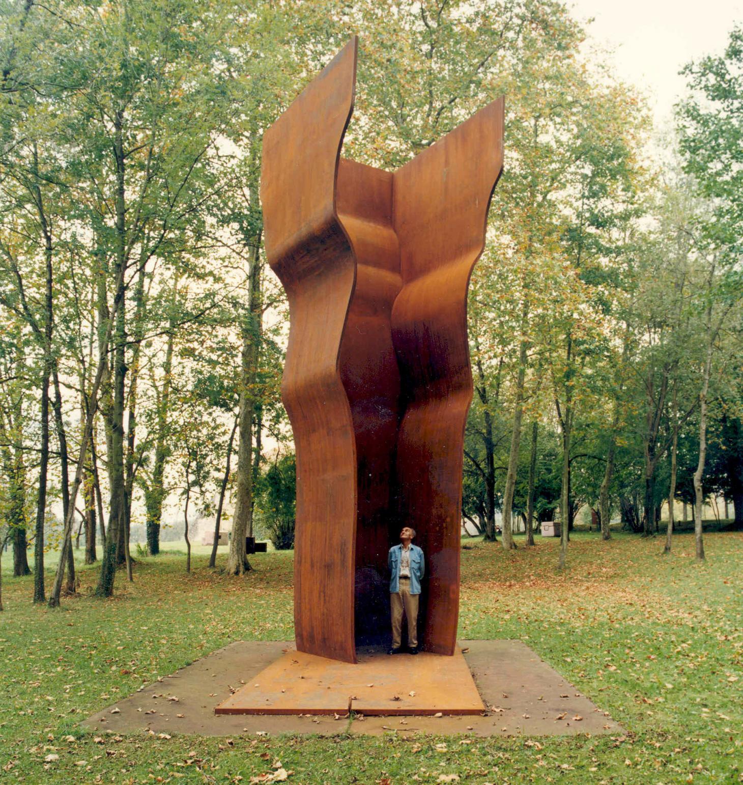 Eduardo Chillida Leku Museum — A monumental corten steel sculpture stands within a forest clearing, its two curved vertical planes forming a narrow passage.