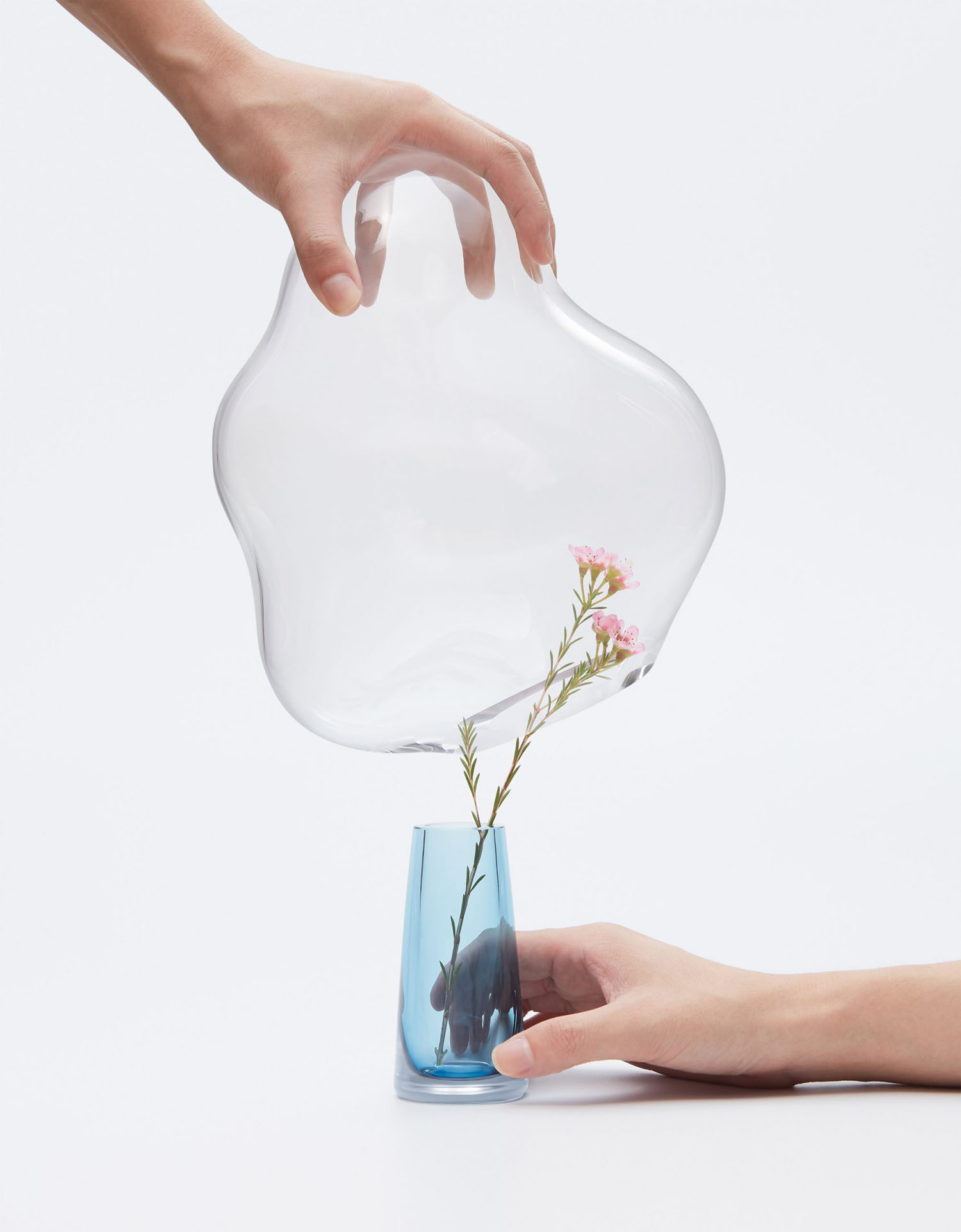 Bubble by Yuhsien Design Studio — A hand tilts a double-walled glass vessel to pour water onto pink carnation stems.