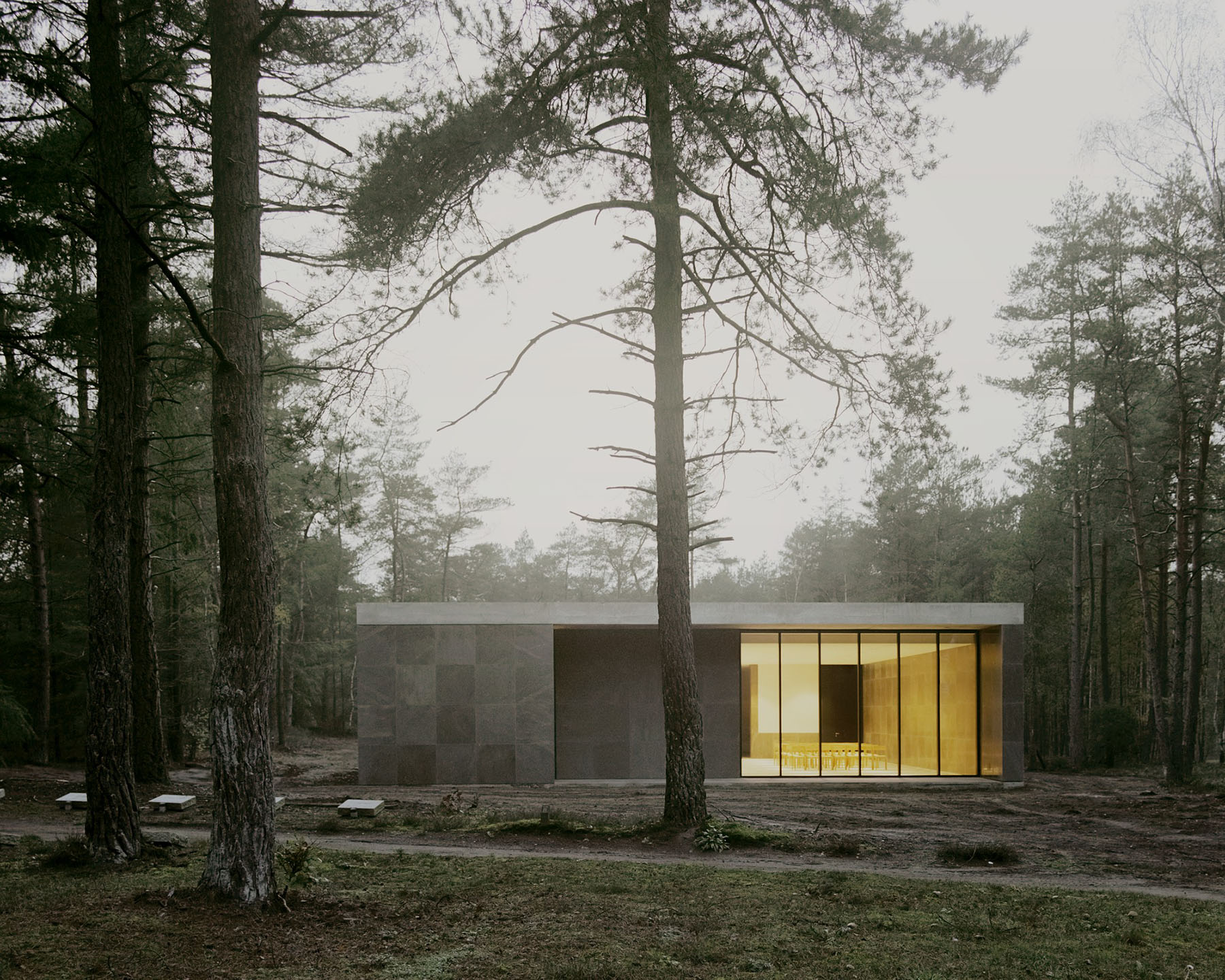 Loenen Pavilion by KAAN Architecten — The Loenen Pavilion emerges from dense pine forest, its monolithic concrete volume punctuated by two mature tree trunks that pass through the structure...