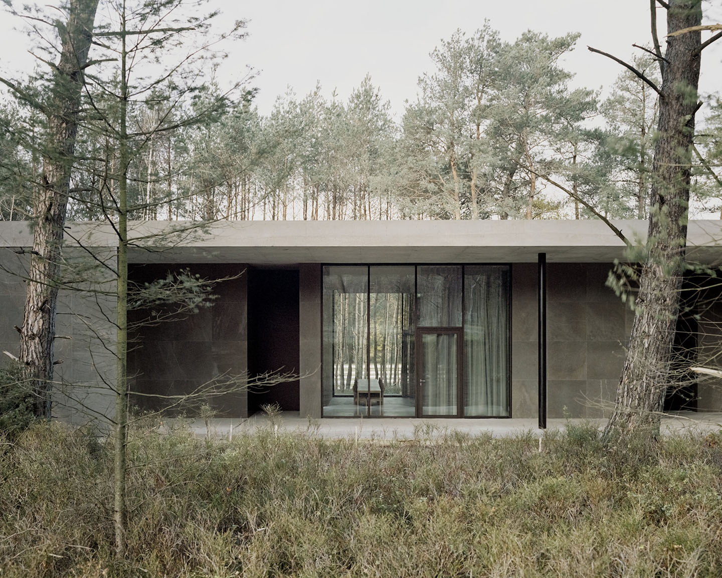 Loenen Pavilion by KAAN Architecten — The pavilion's south-facing facade presents a study in horizontal continuity, with extensive glazing framing the interior's relationship to the forest beyond.