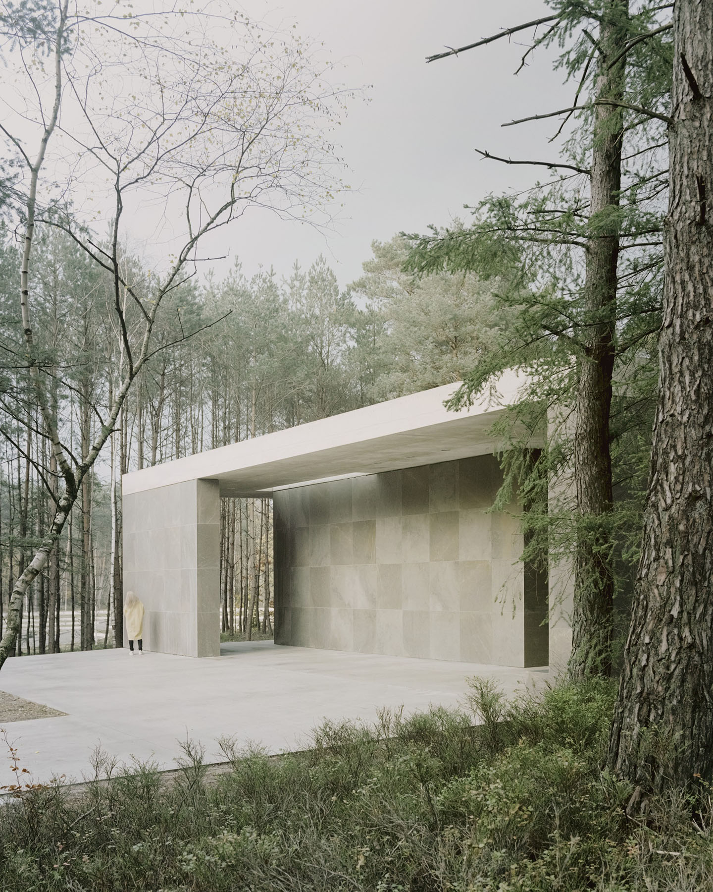 Loenen Pavilion by KAAN Architecten — A monolithic concrete pavilion frames a forest clearing, its planar horizontal roof aligning with surrounding pine canopy.