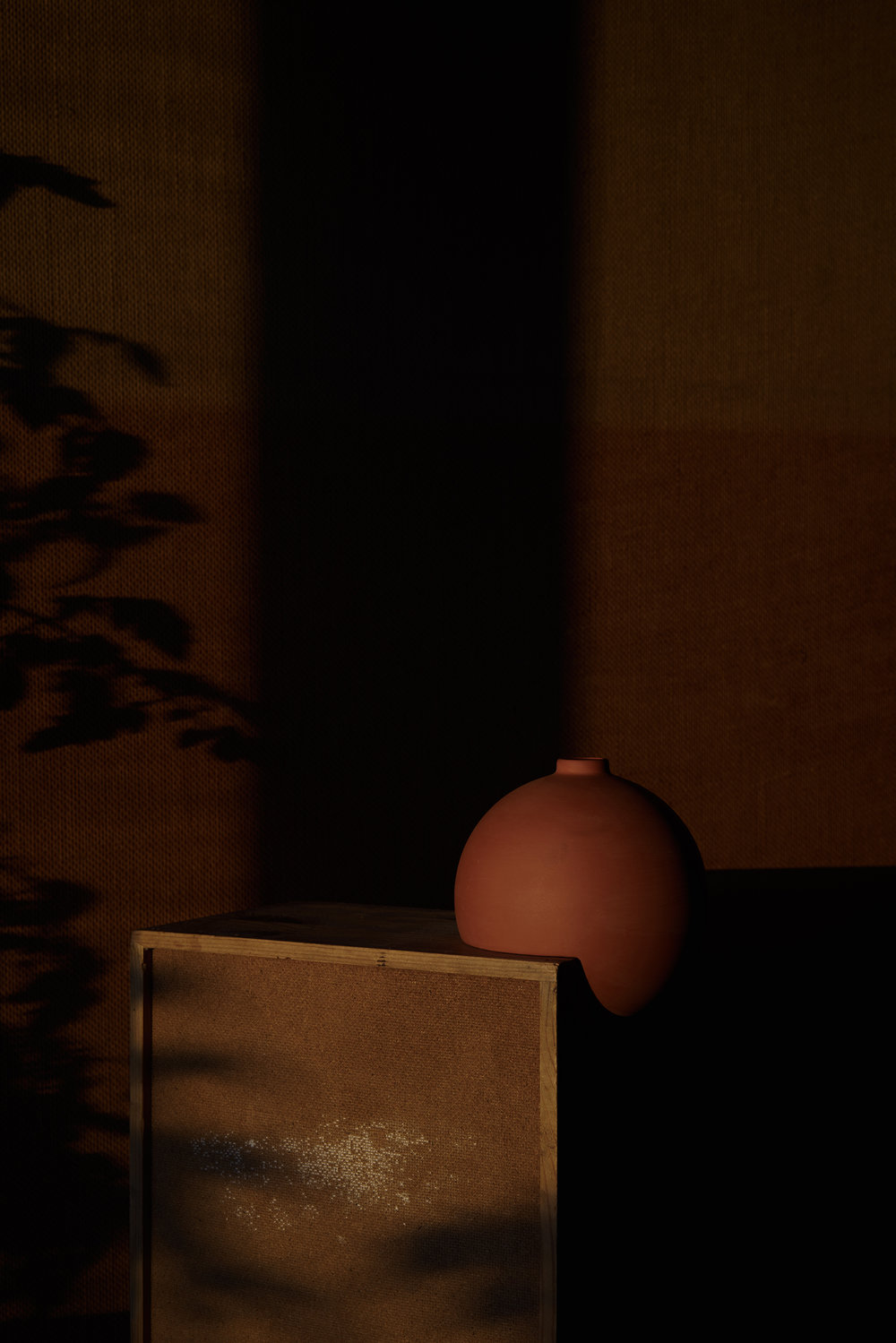 Tumble by Falke Svatun — A slip-cast stoneware vessel in terracotta occupies the right side of the composition, its spherical form rendered in matte finish.