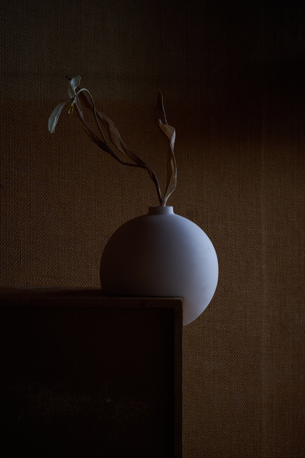 Tumble by Falke Svatun — A slip-cast stoneware vessel with matte finish sits on a dark wooden shelf against a textured neutral wall.